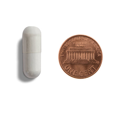 A white capsule being compared to the size of a penny