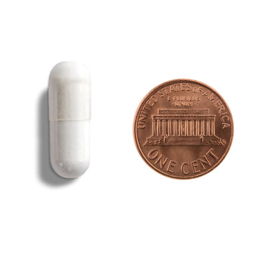A white capsule being compared to the size of a penny