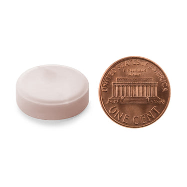 A light pink tablet being compared to the size of a penny