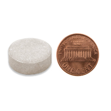 A off-white tablet being compared to the size of a penny
