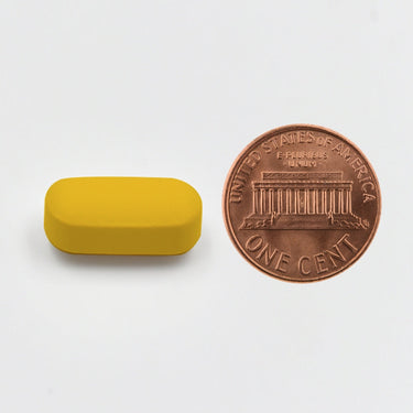 A yellow tablet being compared to the size of a penny