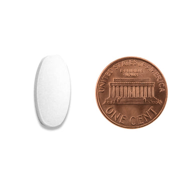 A white oval tablet being compared to the size of a penny
