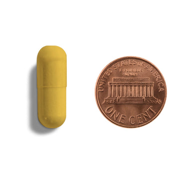 A yellow capsule being compared to the size of a penny