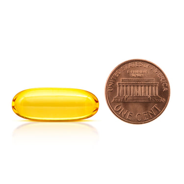 A clear yellow softgel capsule being compared to the size of a penny