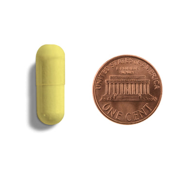 A yellow capsule being compared to the size of a penny
