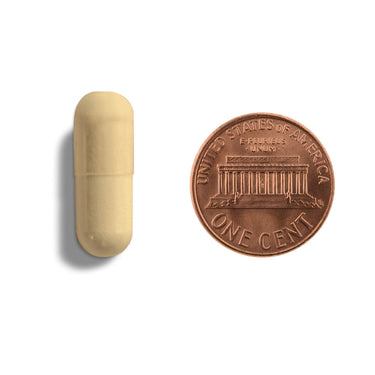 A yellow orange capsule being compared to the size of a penny