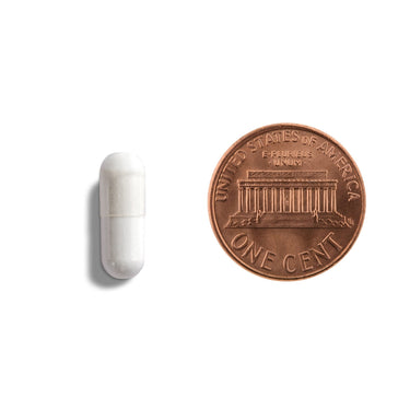 A white capsule being compared to the size of a penny