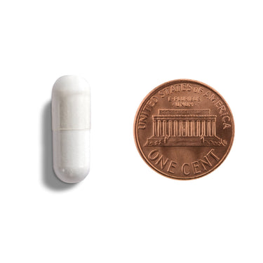 A white capsule being compared to the size of a penny
