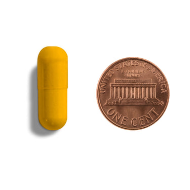 A yellow orange capsule being compared to the size of a penny