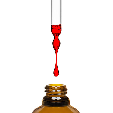 A dropper dripping red Astaxanthin D3 liquid into an amber bottle