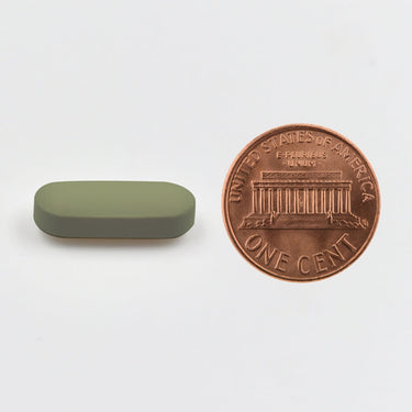 A green tablet being compared to the size of a penny