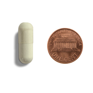A white capsule being compared to the size of a penny