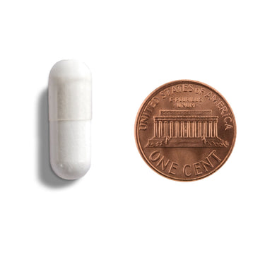 A white capsule being compared to the size of a penny