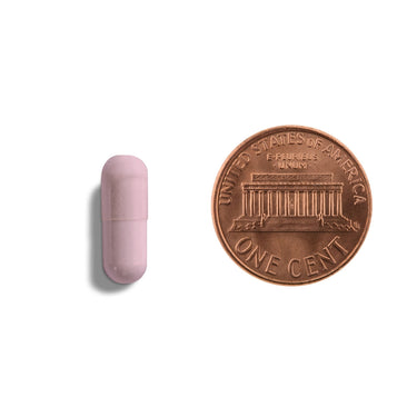 A pink capsule being compared to the size of a penny
