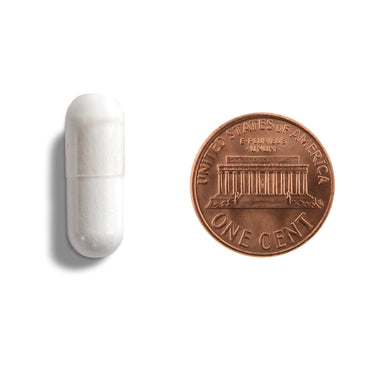 A white capsule being compared to the size of a ruler