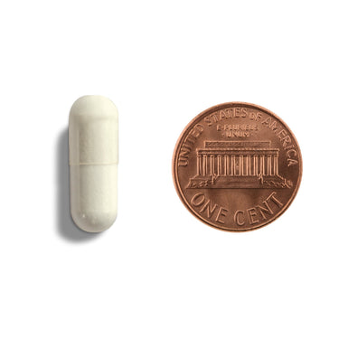 A white capsule being compared to the size of a penny