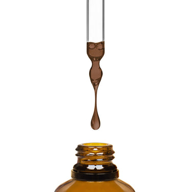 Brown liquid being dripped into an amber bottle by a dropper